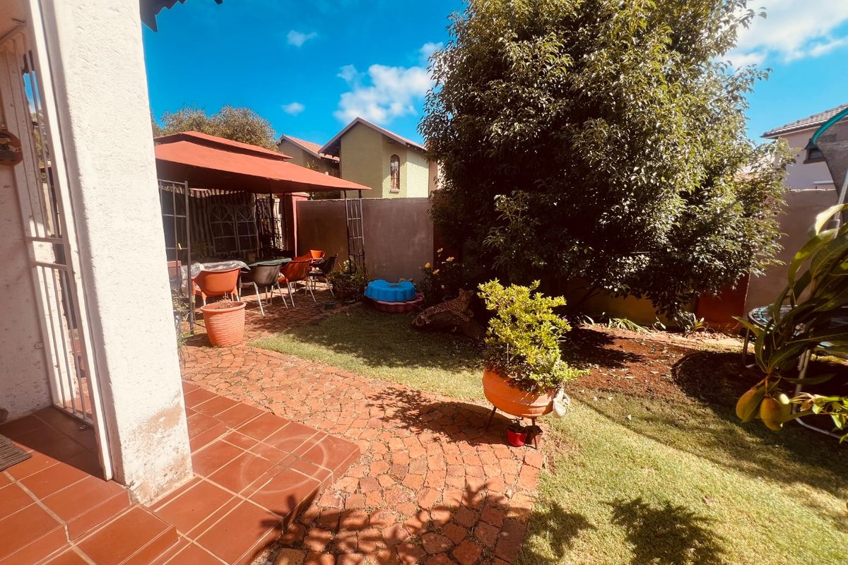 Rear garden area featuring brick paving, a covered patio space, and established boundary walls, providing a private outdoor living environment.