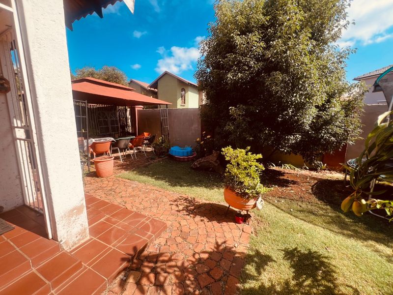 Rear garden area featuring brick paving, a covered patio space, and established boundary walls, providing a private outdoor living environment.