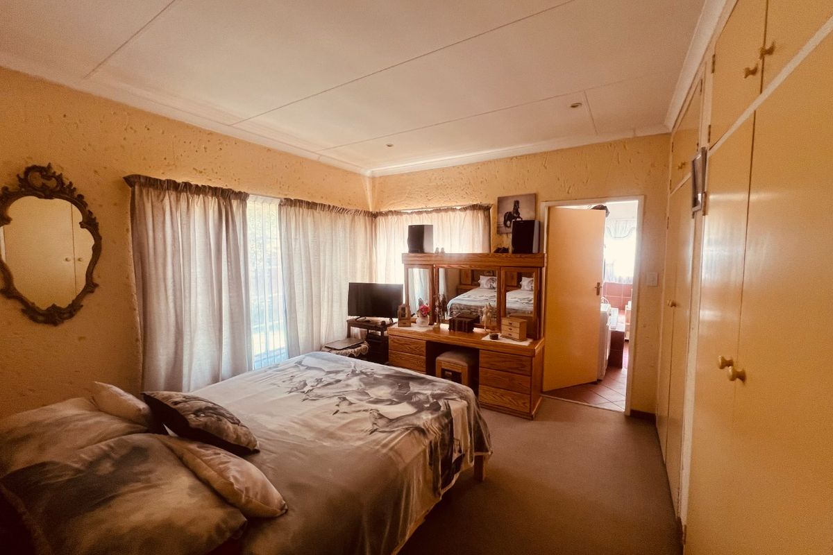 A bedroom featuring built-in cupboards, textured walls, and carpeted flooring, offering a dated aesthetic ready for modernization.