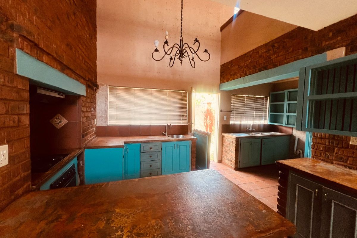 Spacious kitchen featuring exposed brick walls, built-in cabinetry, and tiled flooring, offering a rustic aesthetic with potential for modern updates.