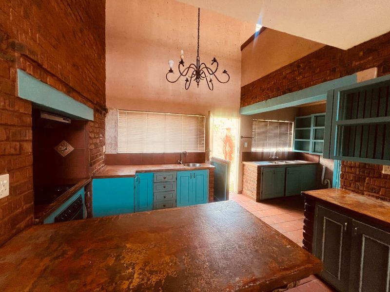 Spacious kitchen featuring exposed brick walls, built-in cabinetry, and tiled flooring, offering a rustic aesthetic with potential for modern updates.