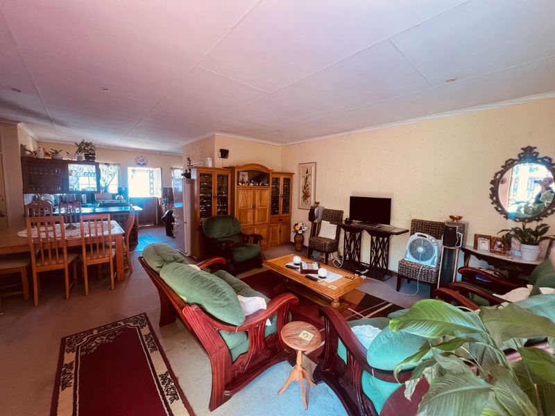 Open-plan living and dining area featuring a connected kitchen space with dated finishes and carpeted flooring throughout the main living zone.