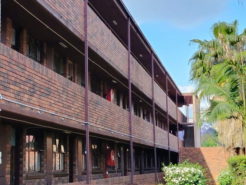 Exterior view of a multi-story apartment building featuring a face brick facade, external walkways, and metal structural supports.