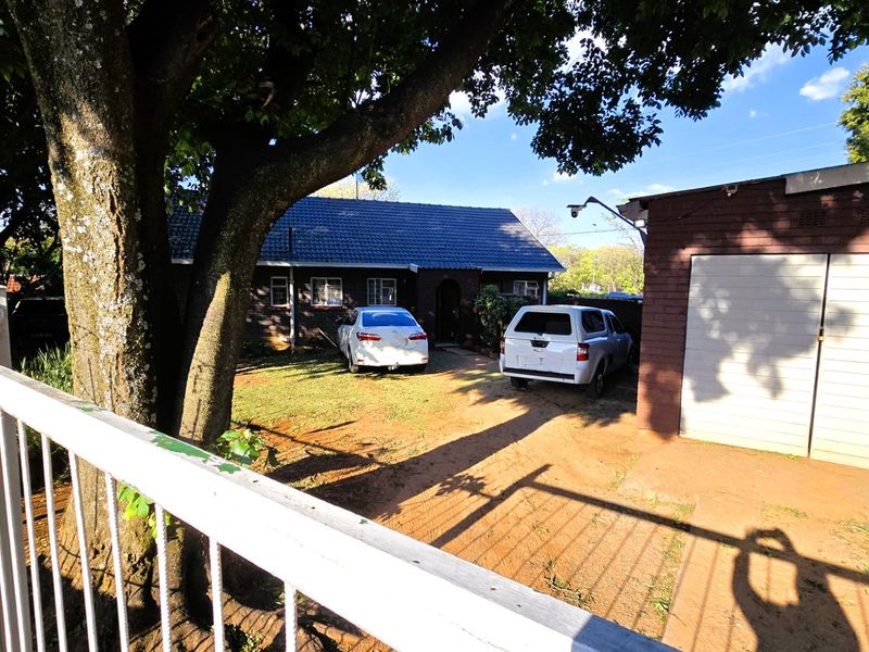 Front view of the property featuring a brick facade, tiled roof, and a detached garage with a paved driveway area.