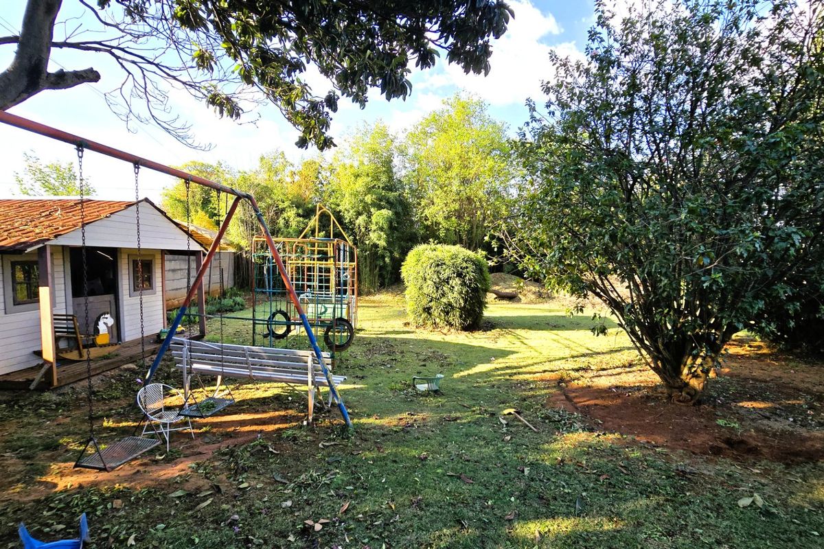 A spacious backyard featuring a detached outbuilding, mature trees, and an expansive lawn area.