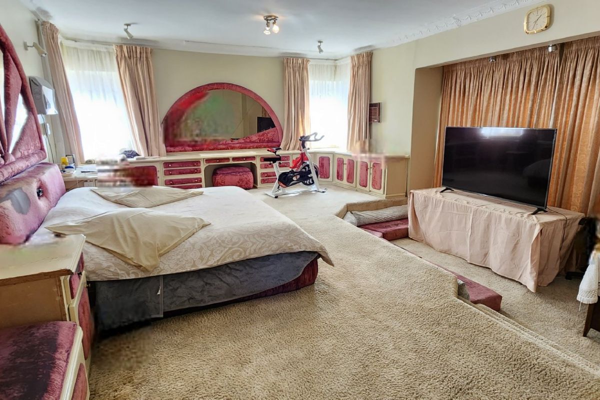 Spacious bedroom featuring a raised floor platform, built-in vanity, and integrated cabinetry, offering significant potential for a modern renovation.