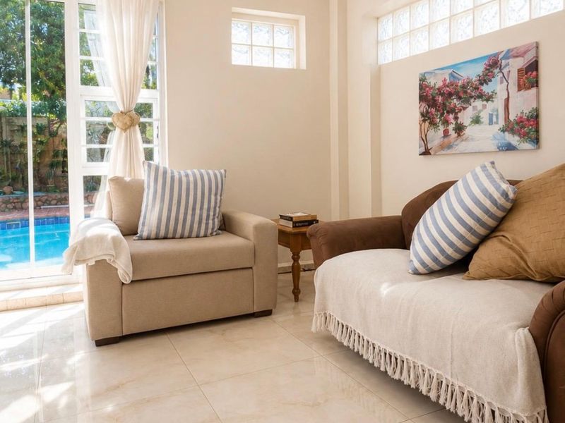 A bright living room featuring polished tile flooring, glass block windows, and a sliding glass door providing direct access to the pool area.