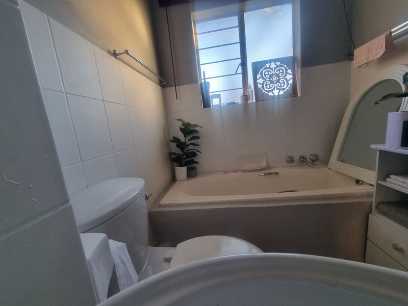 A functional bathroom featuring a built-in bathtub, toilet, and tiled wall finishes, offering a practical layout for renovation or modernization.