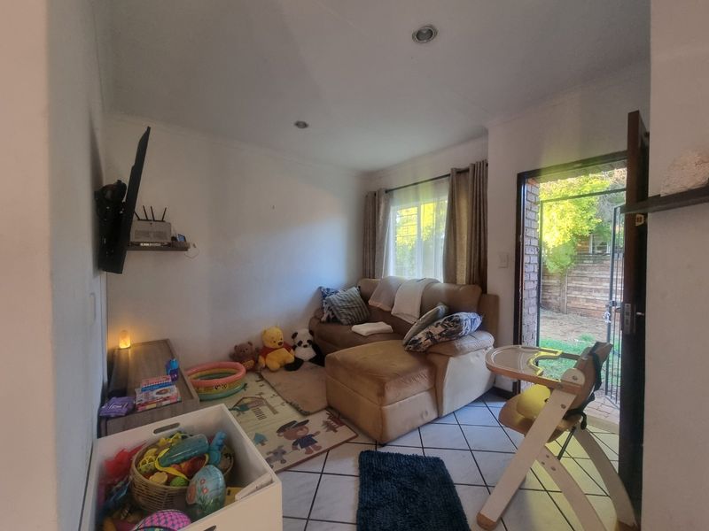 A compact living room featuring tiled flooring, recessed downlighting, and direct access to the rear garden through a sliding door.