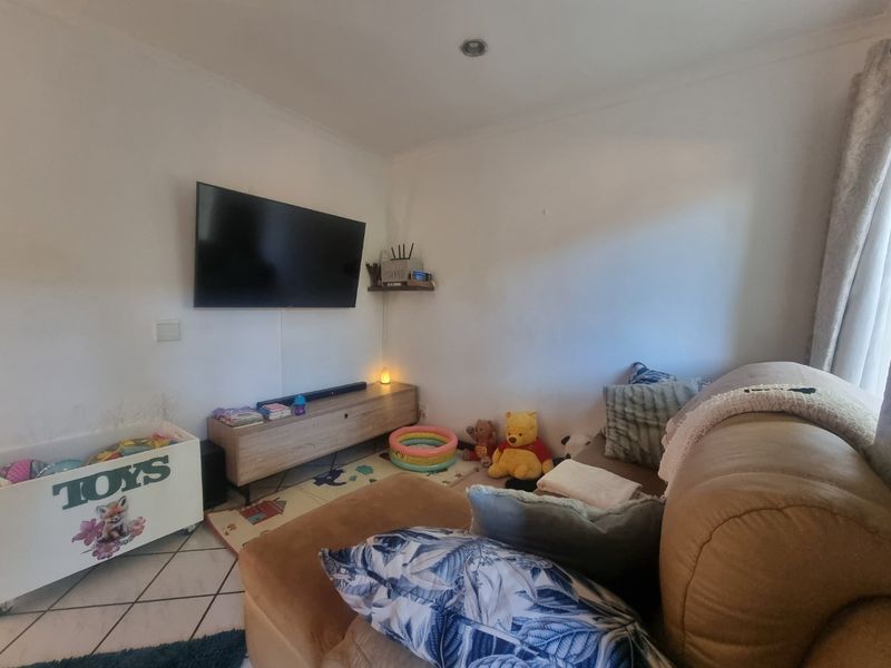 A living room area featuring tiled flooring and recessed ceiling lighting, currently utilized as a family space.