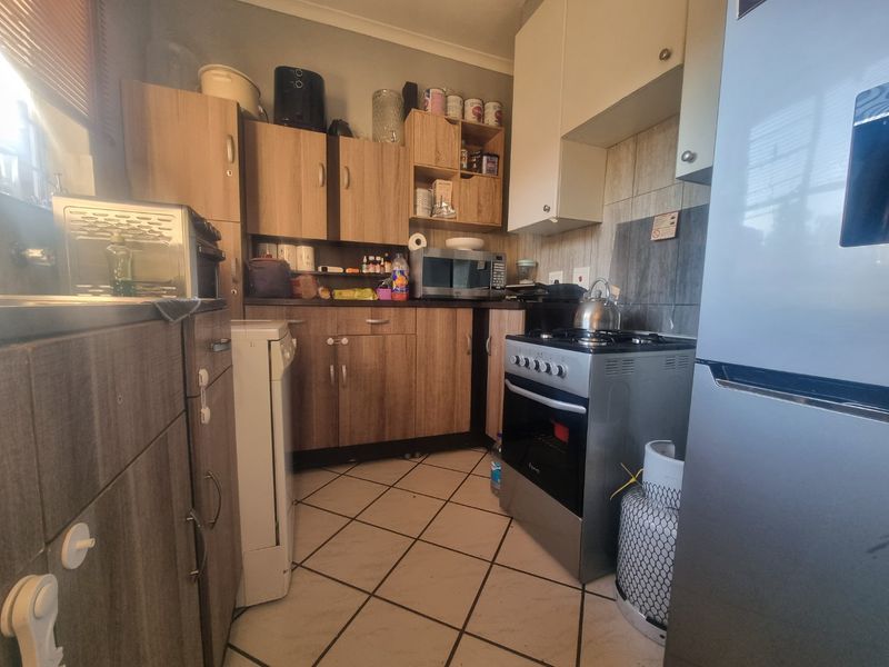 Compact kitchen featuring laminate cabinetry, tiled flooring, a gas stove with oven, and a tiled backsplash.