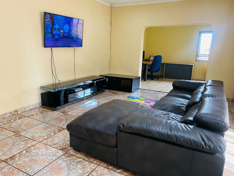 A living room featuring ceramic floor tiles and an open archway leading to an adjacent room, providing a functional and connected living space.