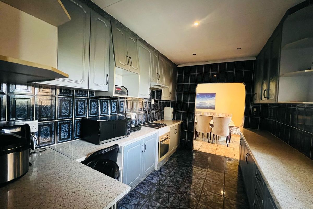A functional kitchen featuring built-in cabinetry, granite countertops, and a tiled backsplash, with an open transition to the adjacent dining area.