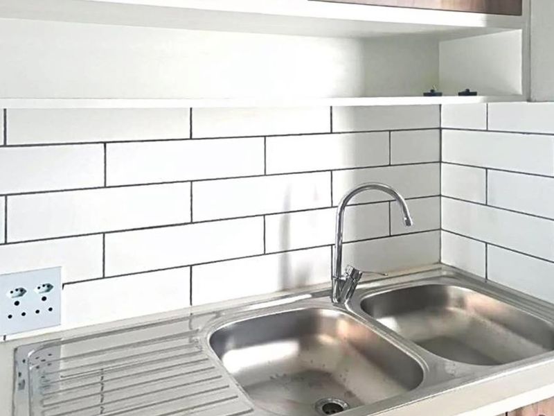 A clean kitchen area featuring a stainless steel double sink with a modern gooseneck faucet and a white subway tile backsplash.
