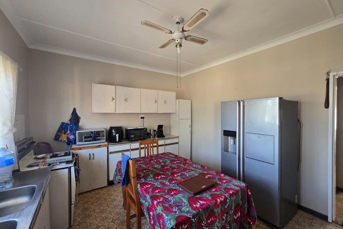 A functional kitchen featuring built-in cabinetry, a double sink, and a ceiling fan, offering potential for modernization and cosmetic updates.