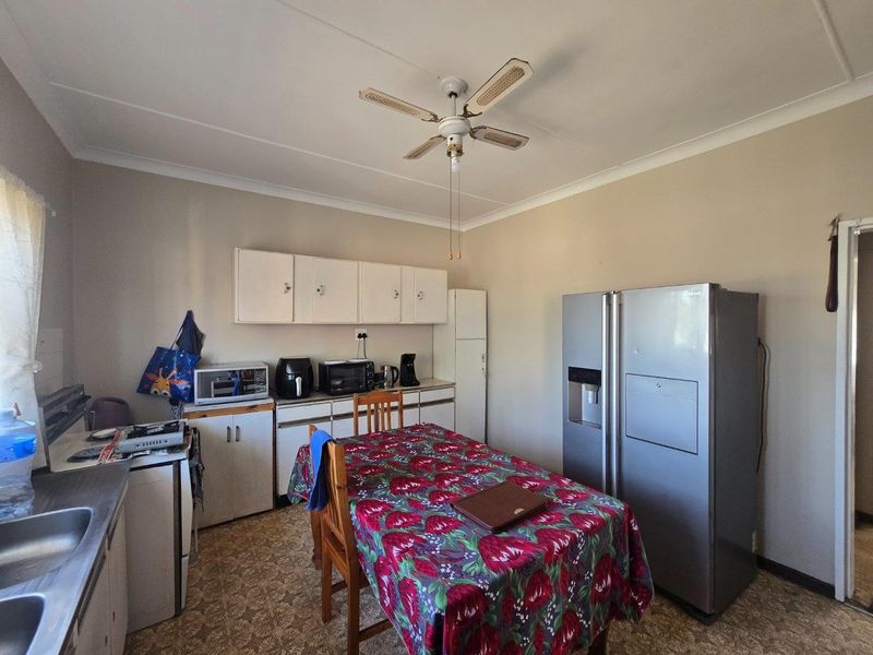 A functional kitchen featuring built-in cabinetry, a double sink, and a ceiling fan, offering potential for modernization and cosmetic updates.