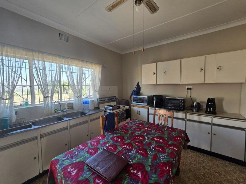 A functional kitchen featuring built-in cabinetry, a double stainless steel sink, and a ceiling fan, offering potential for modernization and cosmetic updates.