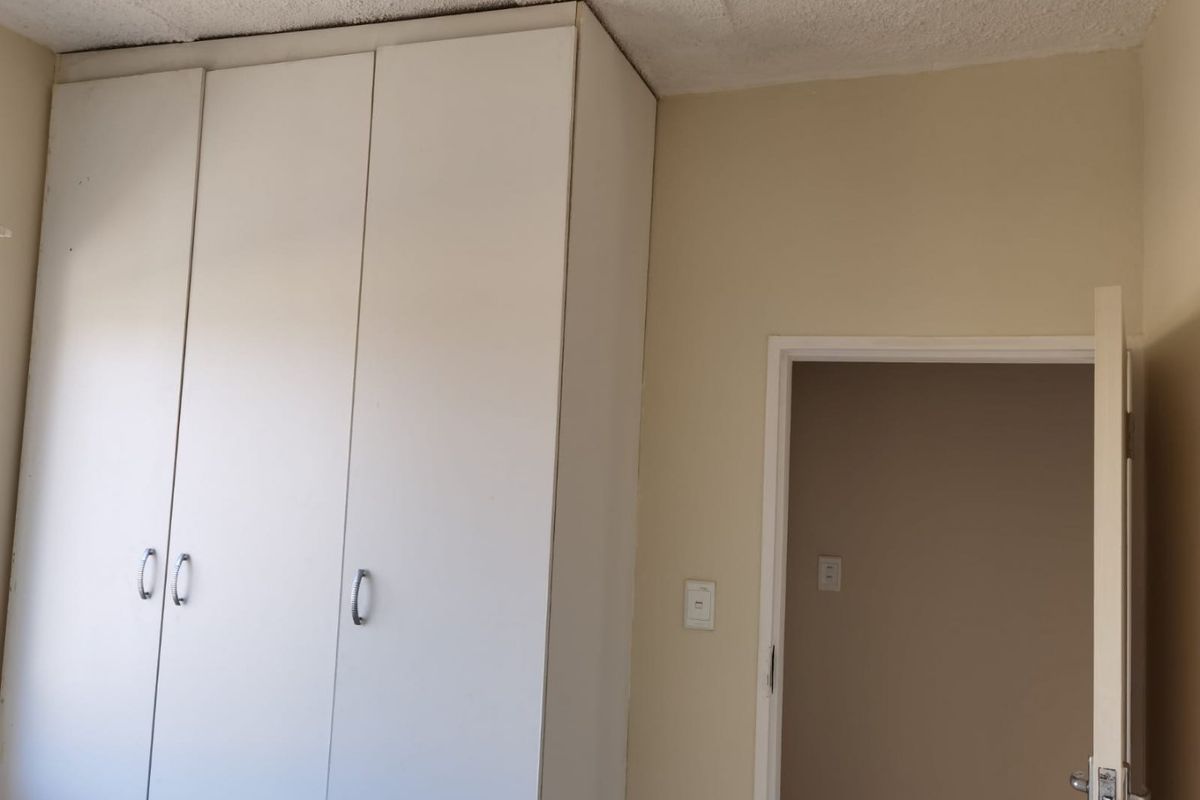 A bedroom featuring a built-in wardrobe and textured ceiling, presenting a blank canvas for potential updates and modernization.