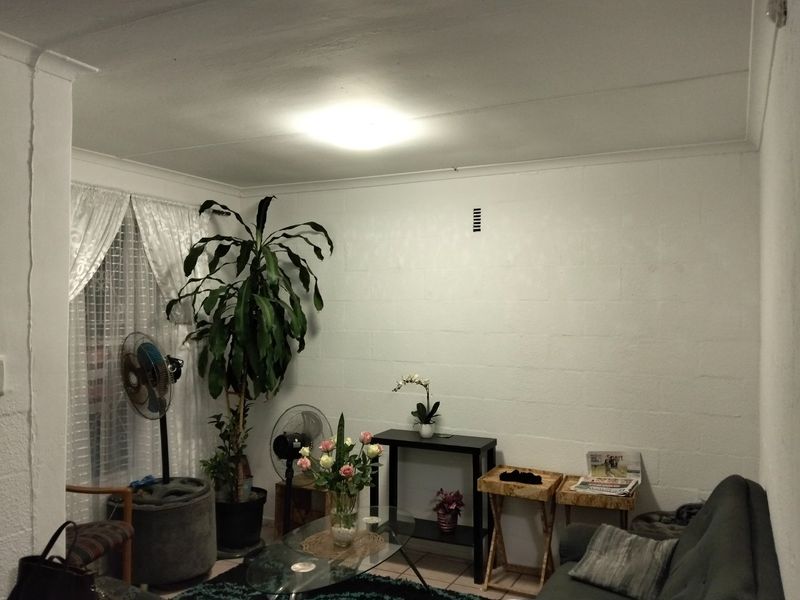 A living room featuring painted blockwork walls, tiled flooring, and cove cornicing, offering a blank canvas for potential interior updates.