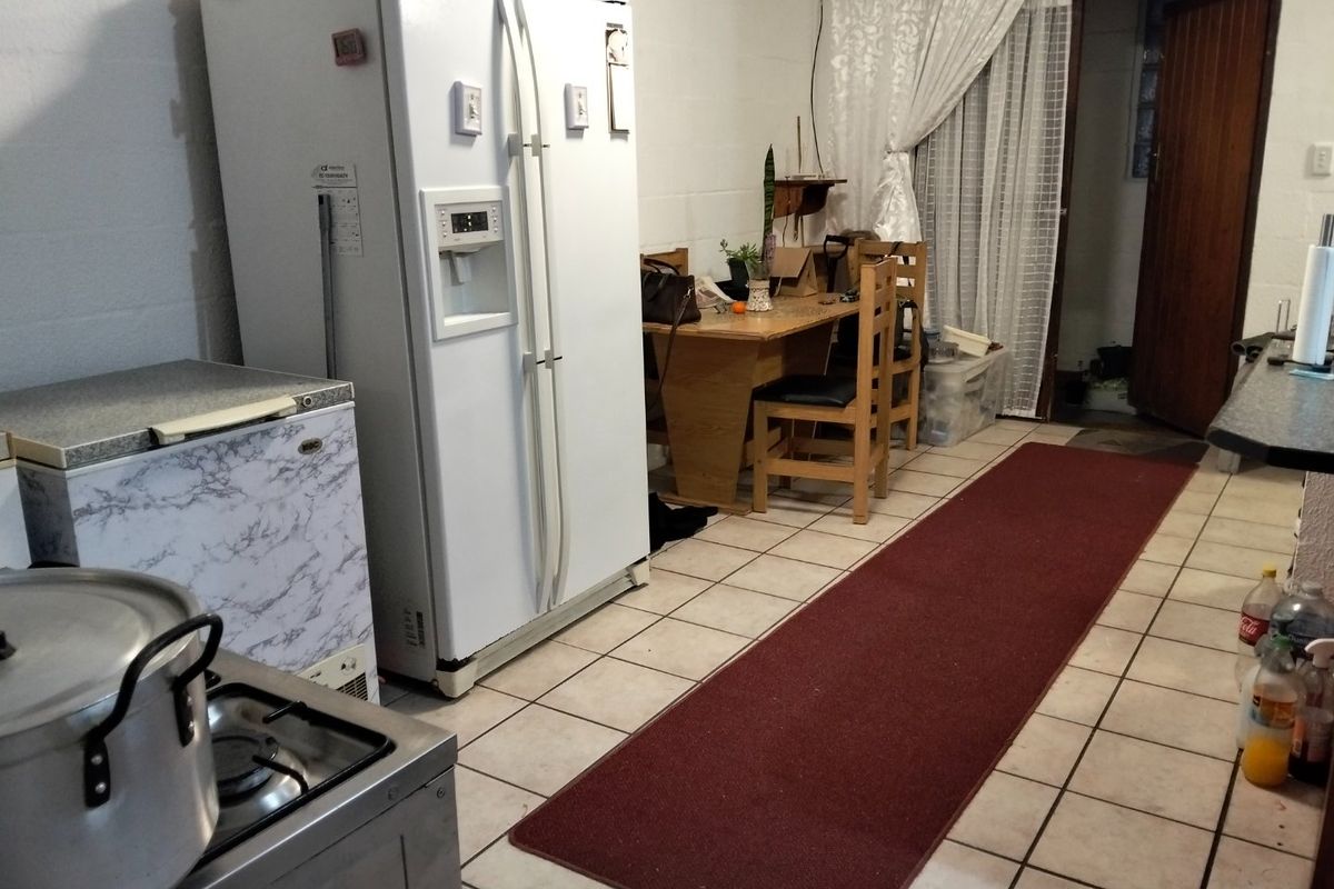 A functional kitchen area featuring tiled flooring, exposed blockwork walls, and a gas stove, offering potential for cosmetic updates and modernization.