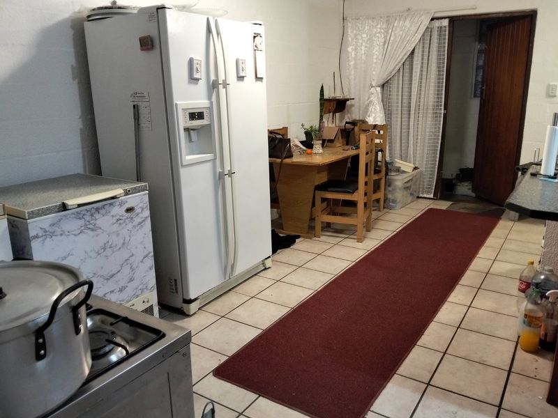 A functional kitchen area featuring tiled flooring, exposed blockwork walls, and a gas stove, offering potential for cosmetic updates and modernization.