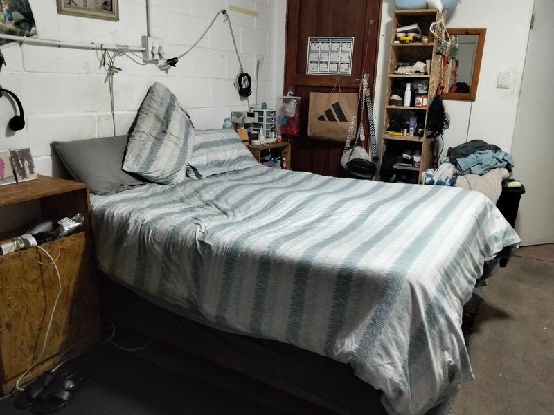 A bedroom featuring exposed brick walls and visible electrical conduit, requiring cosmetic updates and finishing to improve the overall aesthetic and condition.