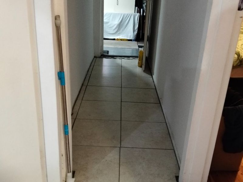 A narrow residential hallway featuring tiled flooring, connecting multiple rooms within the home.