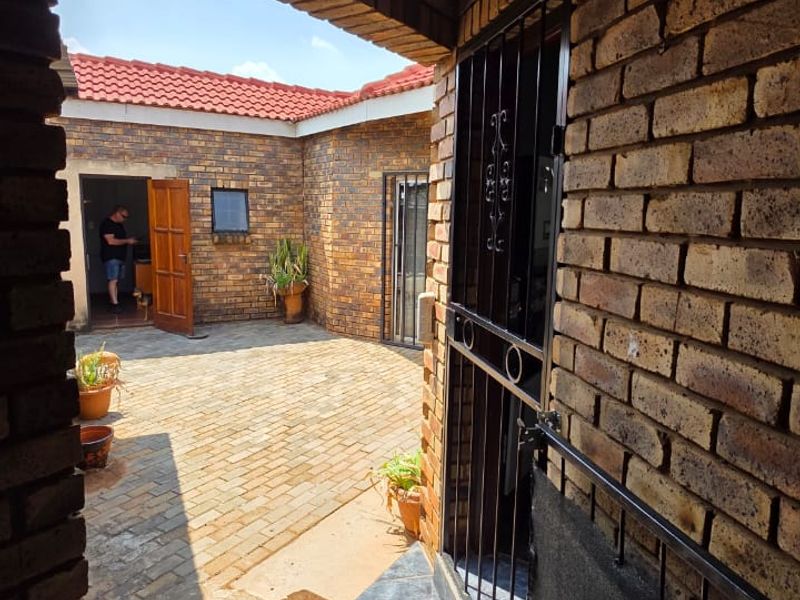 A private paved courtyard area featuring face brick walls, a secure gated entrance, and terracotta roof tiles, providing a functional outdoor space.