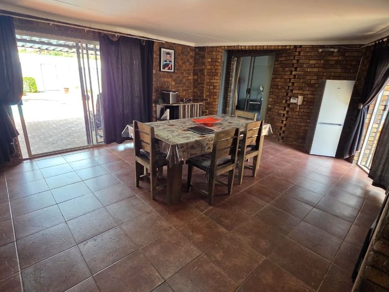 Open plan living and dining area featuring exposed brick walls, tiled flooring, and large sliding glass doors providing access to the outdoor space.
