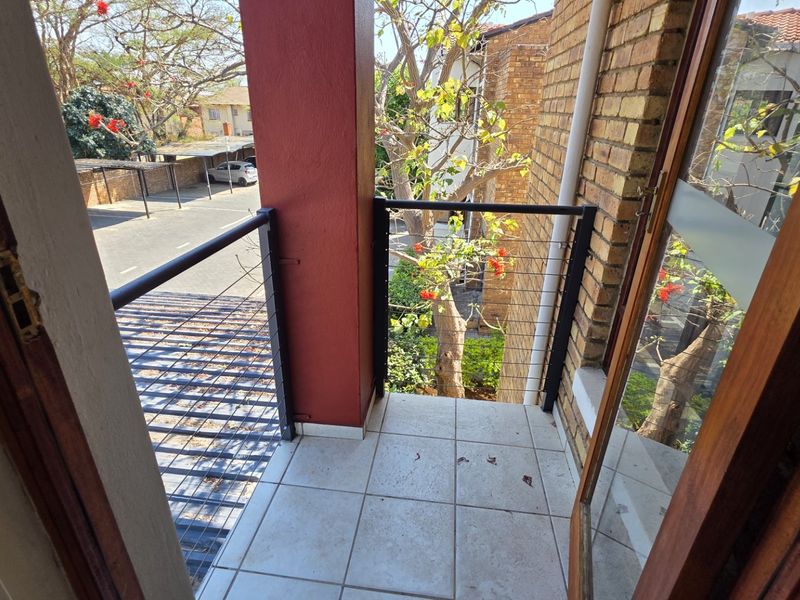 A compact balcony featuring tiled flooring, a metal balustrade, and direct access to the living area through a sliding door.