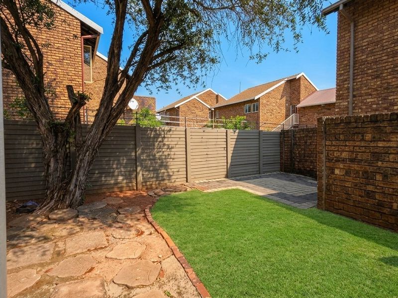 A private rear garden featuring a small lawn, paved patio area, and brick boundary walls, providing a functional outdoor space.