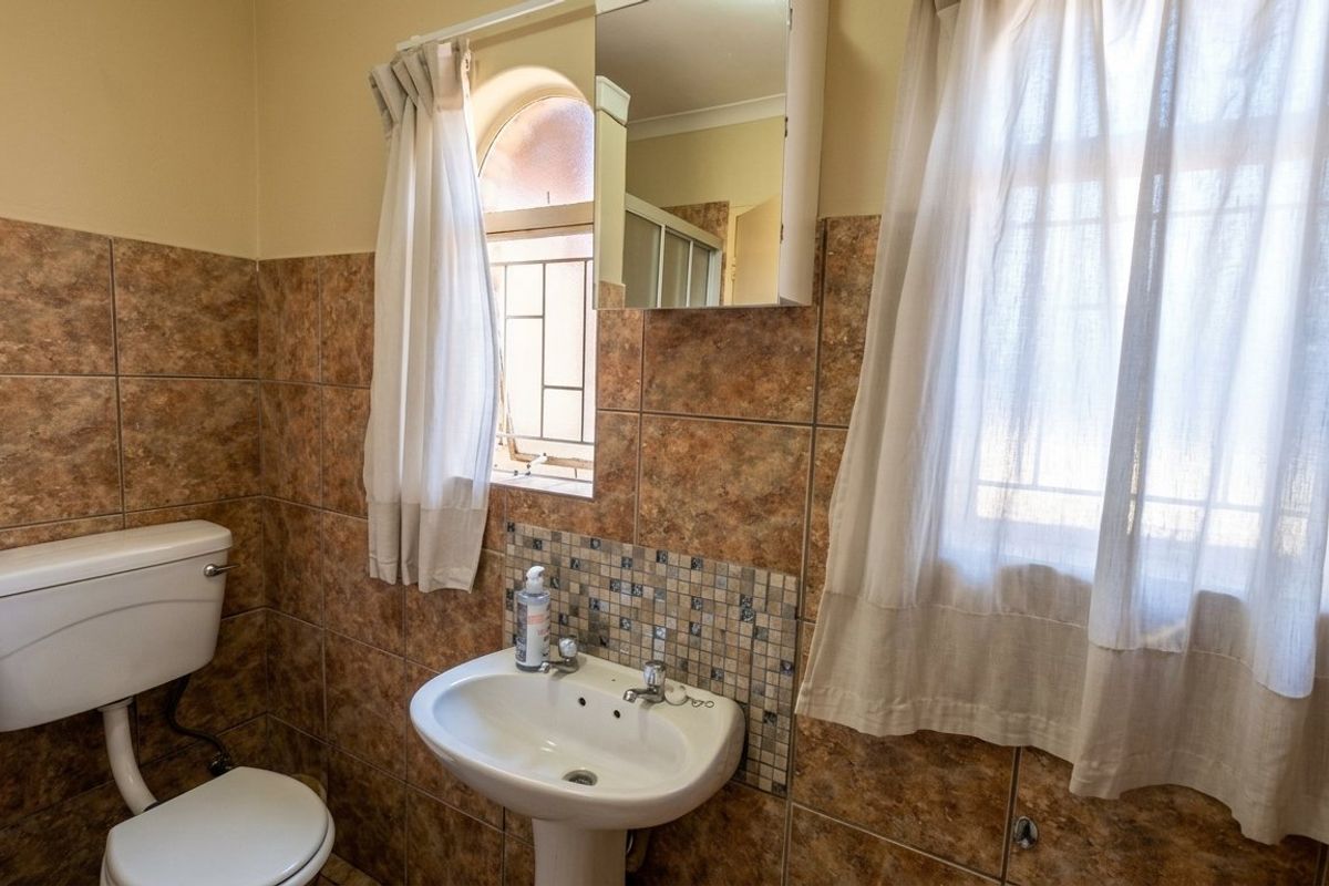 A functional bathroom featuring tiled walls, a pedestal basin, and a wall-mounted medicine cabinet.