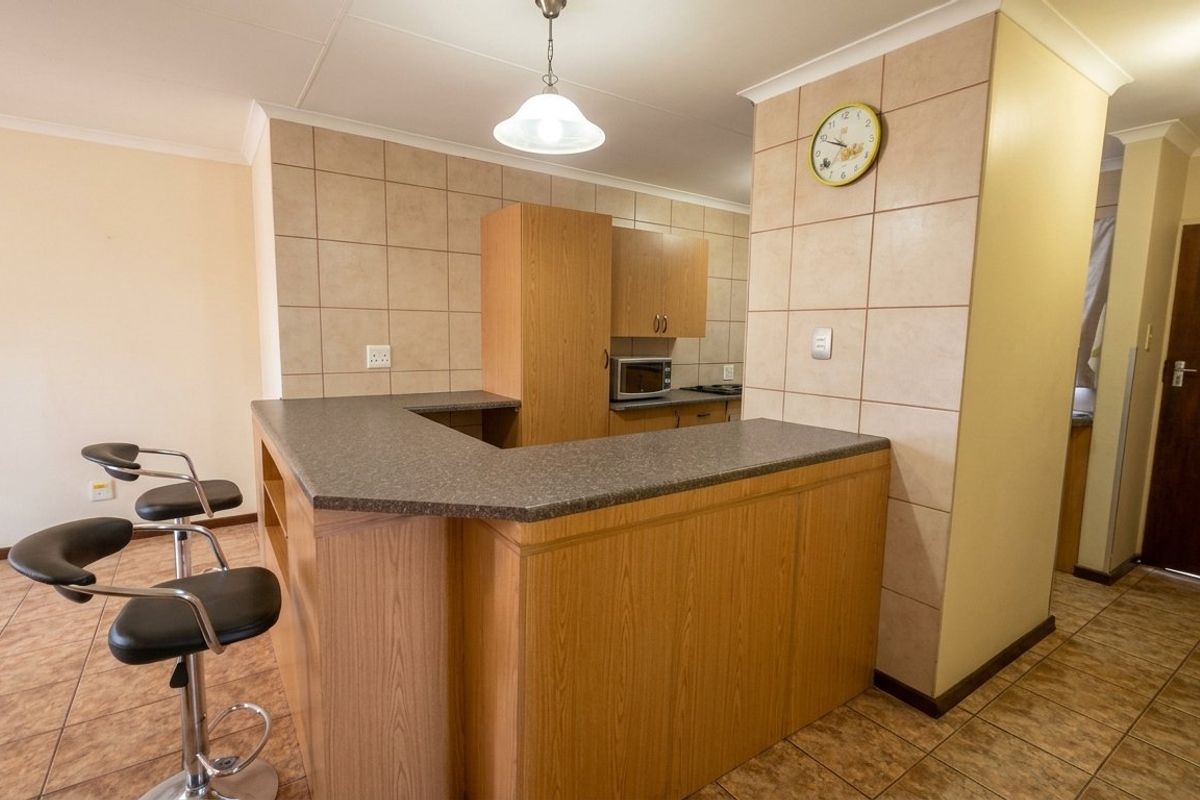 A functional kitchen featuring laminate cabinetry, a breakfast bar, tiled backsplash, and tiled flooring, providing a practical layout for daily use.