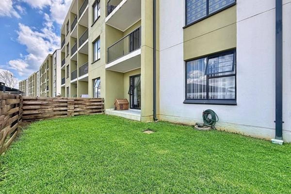 Ground floor apartment unit featuring a private garden area, timber fencing, and access to a balcony with sliding door entry.