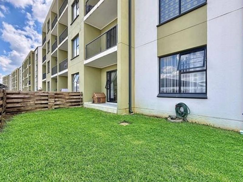 Ground floor apartment unit featuring a private garden area, timber fencing, and access to a balcony with sliding door entry.
