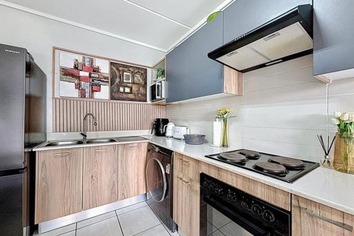 Modern kitchen featuring wood-grain cabinetry, sleek grey overhead cupboards, integrated appliances, tiled backsplash, and durable tiled flooring.