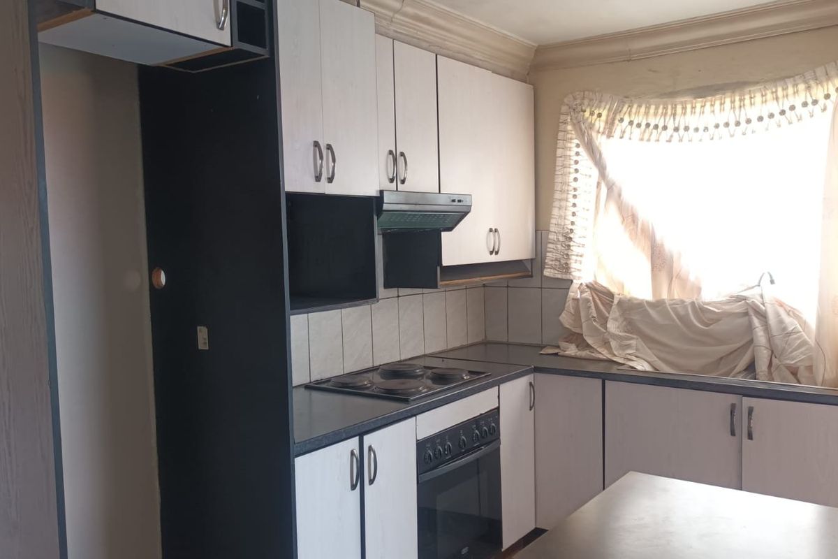 A dated kitchen featuring built-in cabinetry, an electric hob, an oven, and an extractor fan, offering potential for a modern renovation.