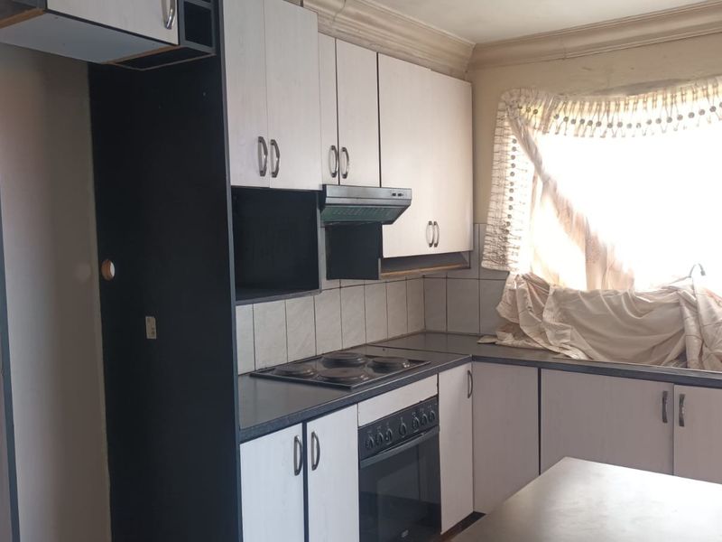 A dated kitchen featuring built-in cabinetry, an electric hob, an oven, and an extractor fan, offering potential for a modern renovation.