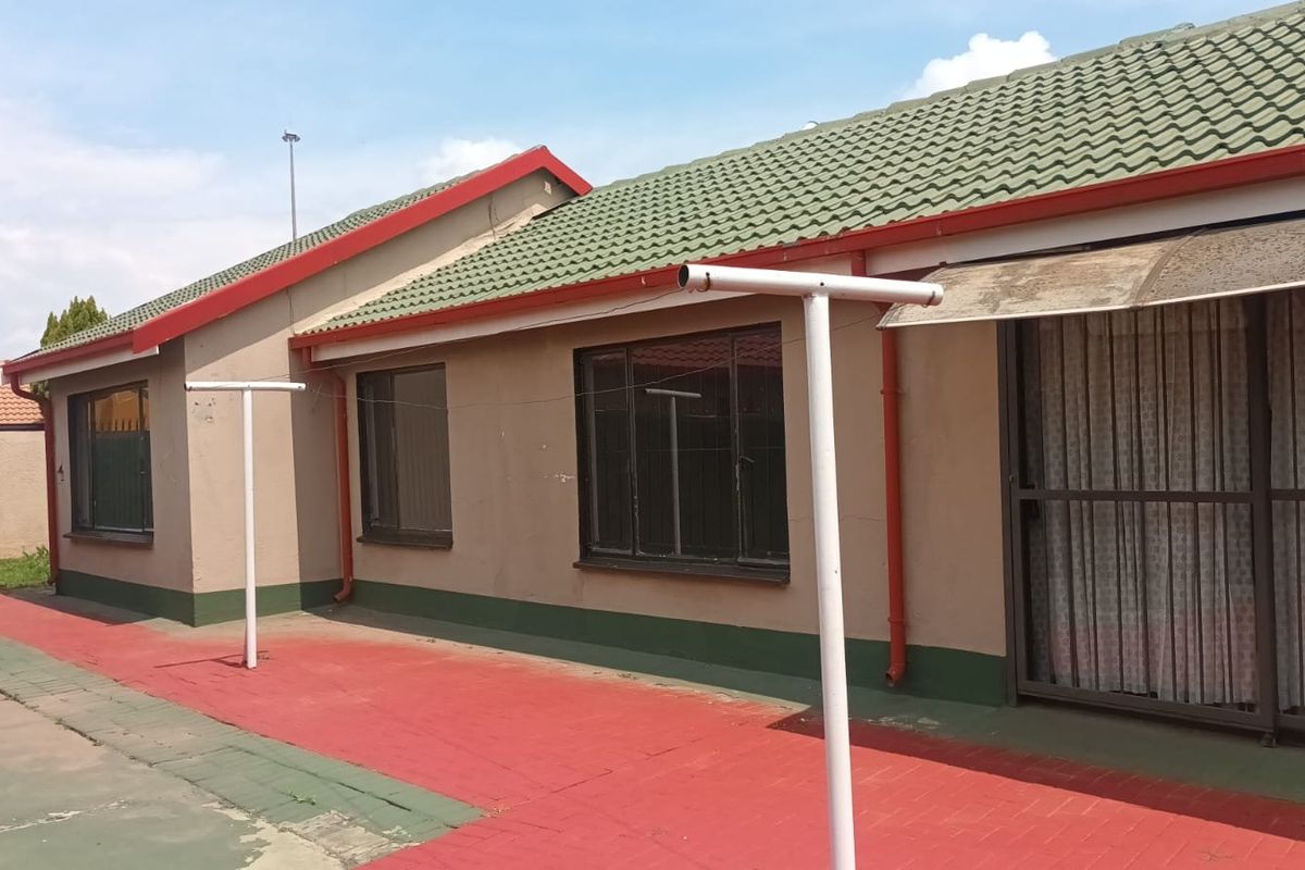 Rear exterior view of the house featuring a tiled roof, paved patio area, and sliding door access.