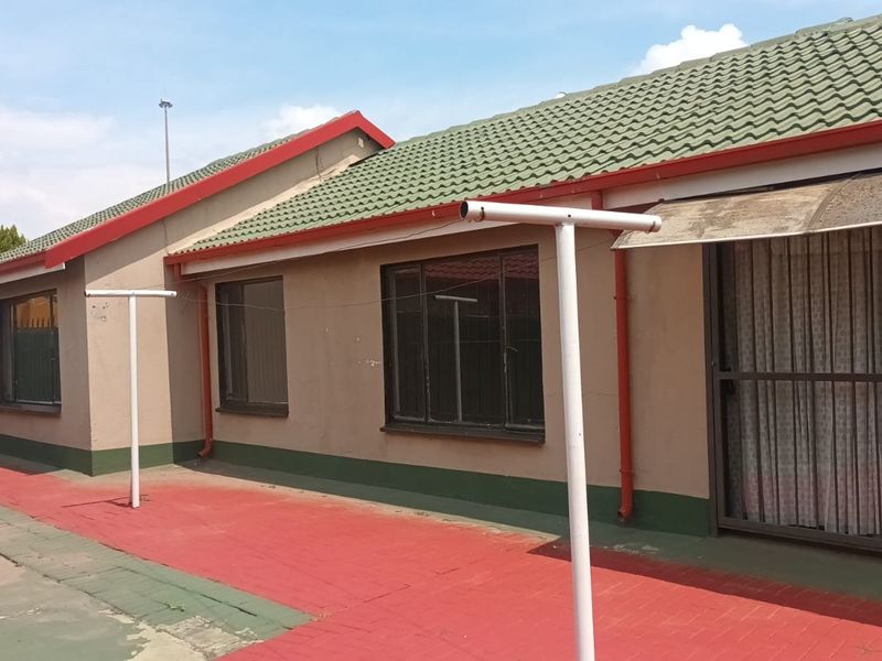 Rear exterior view of the house featuring a tiled roof, paved patio area, and sliding door access.