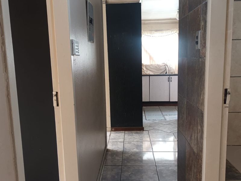 A functional hallway connecting living spaces, featuring tiled flooring and access to adjacent rooms with built-in cabinetry visible in the background.