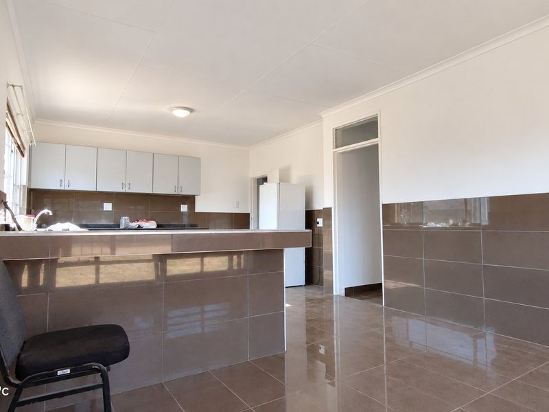 A functional kitchen area featuring tiled walls and flooring, built-in cabinetry, and a breakfast bar counter.