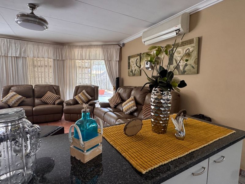 Open-plan living area featuring a granite-topped kitchen island, split-system air conditioning, and direct access to an outdoor patio through sliding glass doors.