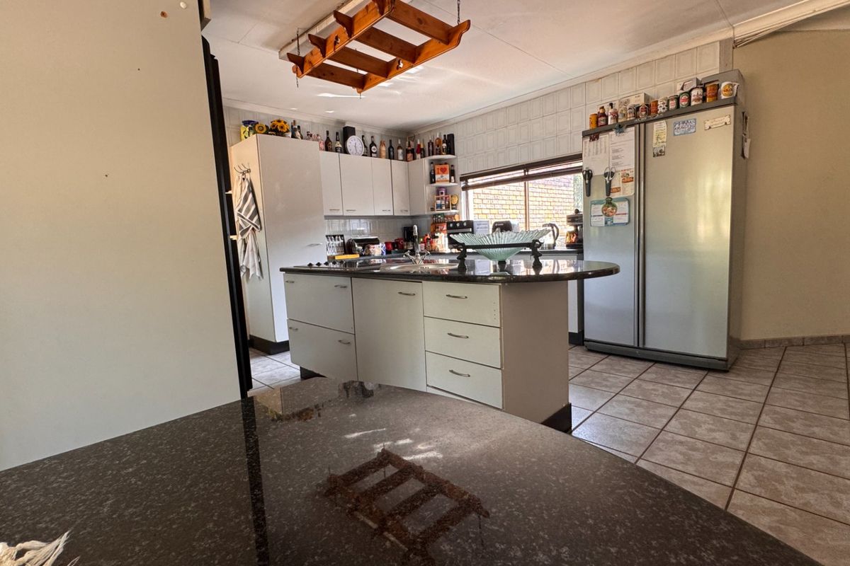 Functional kitchen featuring a central island with granite countertops, ample built-in cabinetry, and tiled flooring, offering a practical layout for daily use.