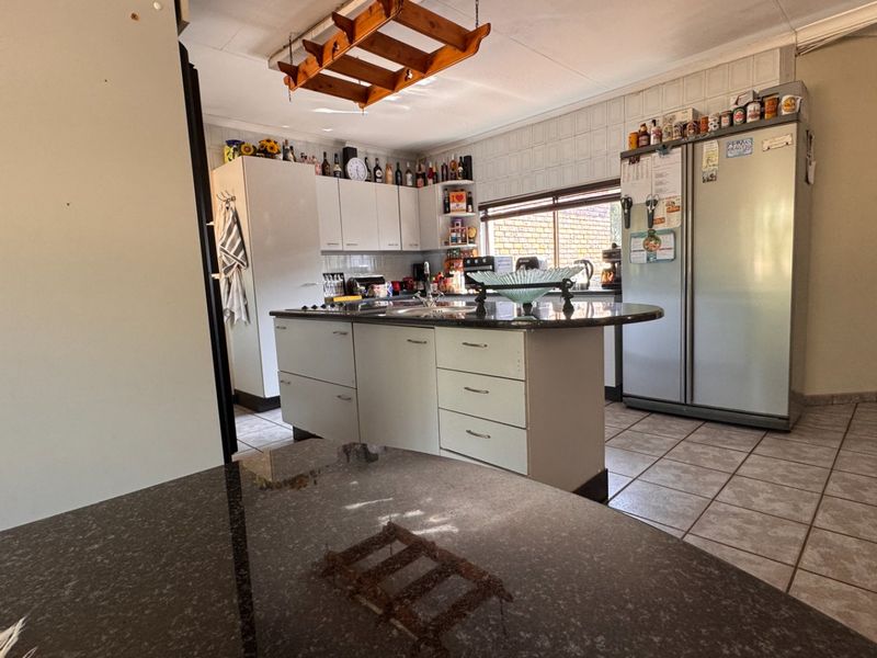 Functional kitchen featuring a central island with granite countertops, ample built-in cabinetry, and tiled flooring, offering a practical layout for daily use.