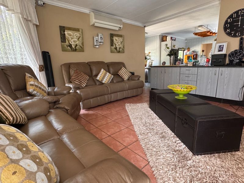 Open-plan living area featuring tiled flooring, built-in cabinetry, and a wall-mounted air conditioning unit, providing a functional and connected living space.