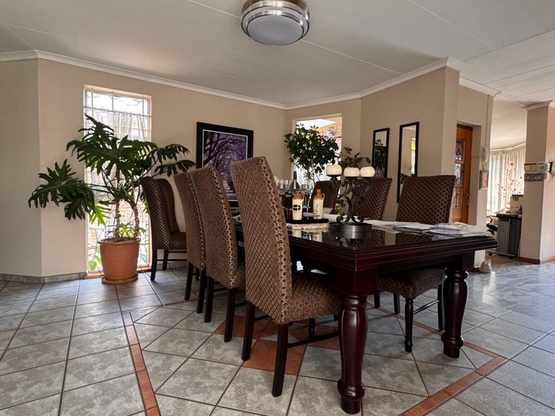 A dining room featuring tiled flooring with decorative inlay, coved cornicing, and natural light from adjacent windows and doorways.