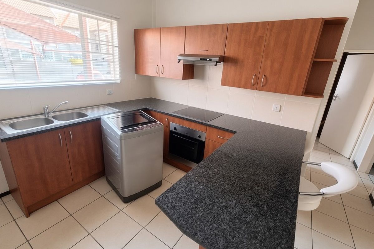 Functional kitchen featuring laminate cabinetry, granite countertops, built-in oven, electric hob, extractor fan, and tiled flooring with a breakfast nook area.