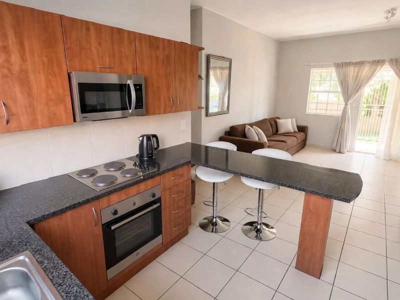 Open-plan kitchen and living area featuring wood-finish cabinetry, granite countertops, built-in appliances, and direct access to a patio through sliding glass doors.