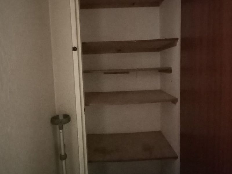A small utility closet or pantry space featuring built-in wooden shelving, suitable for storage or organization.
